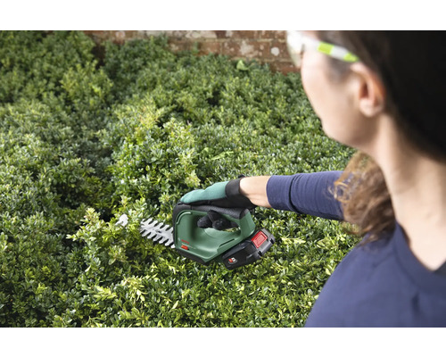 Žena stříhá živý plot akumulátorovými nůžkami na živý plot