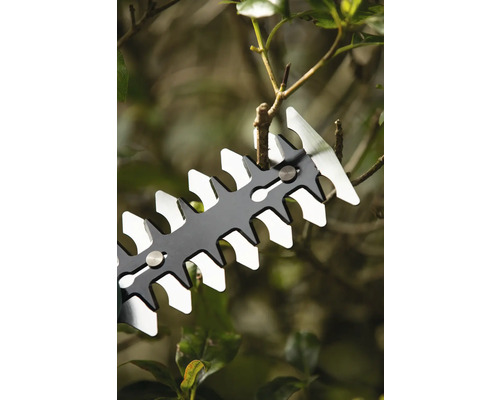 Detailní záběr nůžek na živý plot stříhajících větve