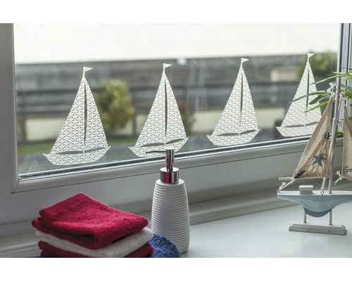 Dekorativní okno s motivem plachetnice, doplněné ručníky a dávkovačem mýdla