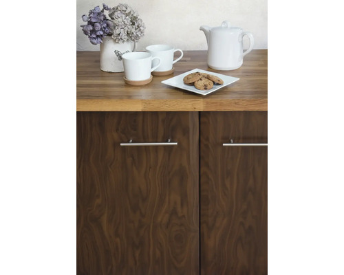 Kuchyňská scéna s nádobím, pečivem a květinovou výzdobou na pracovní desce nad skříňkou