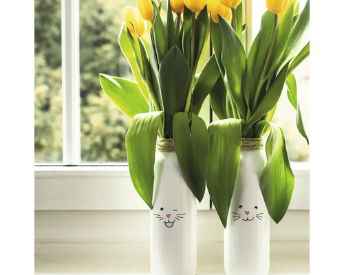 Dvě vázy s motivy zajíčků a žlutými tulipány na okenním parapetu.
