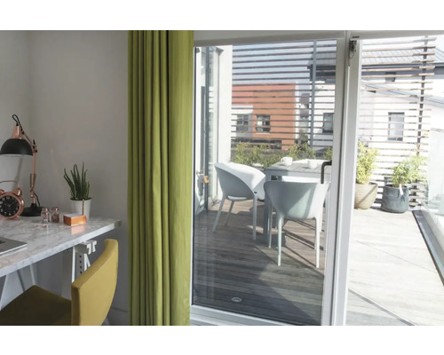 Světlá místnost s psacím stolem, židlí a závěsem, výhled na terasu se stolem a židlemi