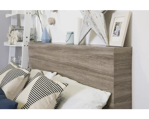 Postel s čelem v dřevěném vzhledu a odkládací plochou s dekorativními předměty a polštáři