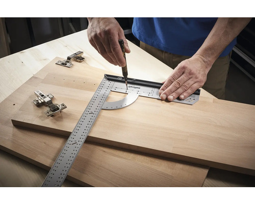 Osoba používá úhloměr a tužku k vytváření značek na dřevěné desce vedle závěsů.