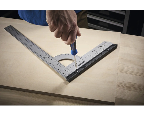 Řemeslník šroubuje multifunkční úhelník na dřevěnou desku pomocí šroubováku