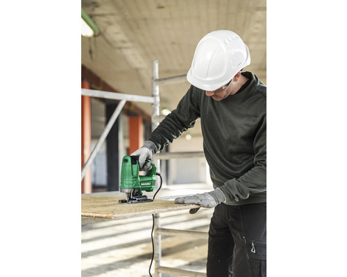 Muž s ochrannou helmou řeže dřevo přímočarou pilou značky HiKOKI.