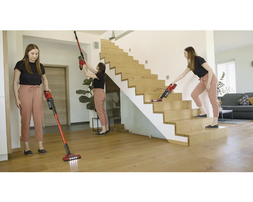 Žena používá akumulátorový vysavač v domě na podlaze, na stropě a na schodech