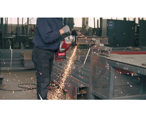 Muž řeže úhlovou bruskou kus kovu.