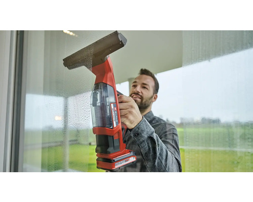 Muž čistí okna pomocí akumulátorové stěrky na okna