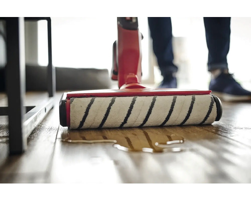 Detailní pohled na mycí vysavač v akci na dřevěné podlaze.