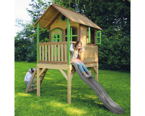 Dřevěný hrací domek se skluzavkou a dvěma hrajícími si dětmi na zahradě.
