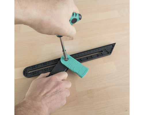 Osoba nastavuje úhelníkový přípravek šroubovákem na dřevěné podlaze.