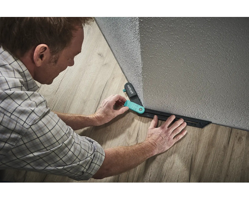 Muž používá rýsovací šablonu Wolfcraft k pokládce laminátu.