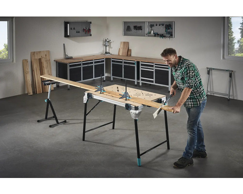 Vybavení dílny s pracovní lavicí, dřevěnými deskami a kutil, který řeže desku