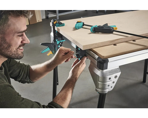 Muž montuje pracovní stůl se šroubovými svorkami pro zpracování dřeva