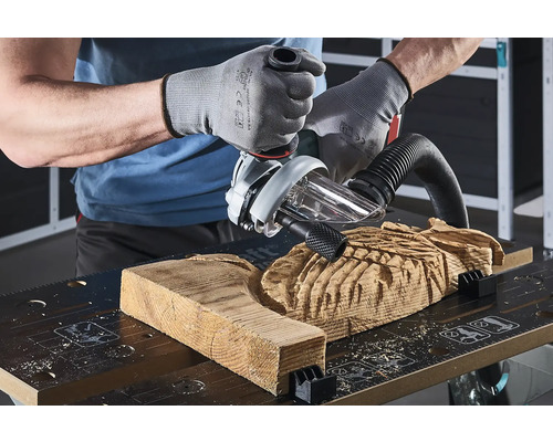 Řemeslník opracovává kus dřeva horní frézkou na pracovním stole.