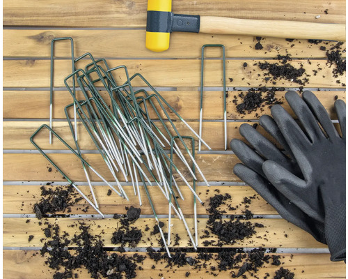 Zahradní snímek s kolíky, gumovou paličkou a zahradními rukavicemi na dřevěném stole