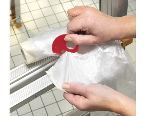 Osoba používá červený odtrhávač sáčků ve tvaru slona na stojanu na role.