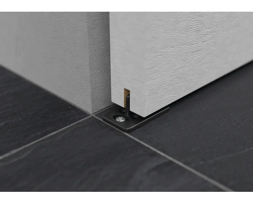 Detail posuvného vedení dveří na tmavé dlažbě