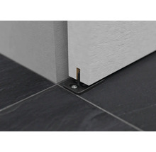 Detail posuvného dveřního systému s podlahovou vodicí lištou na dlažbě.