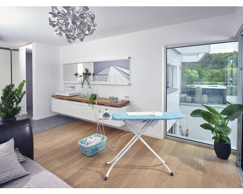 Obývací pokoj s žehlicím prknem, žehličkou, košem na prádlo a pokojovými rostlinami