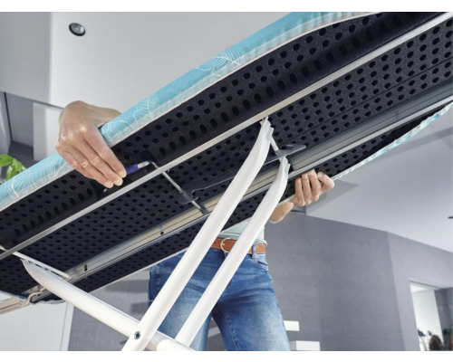 Osoba nese žehlicí prkno s podstavcem