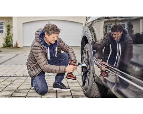 Muž mění kolo u auta pomocí akumulátorového rázového utahováku