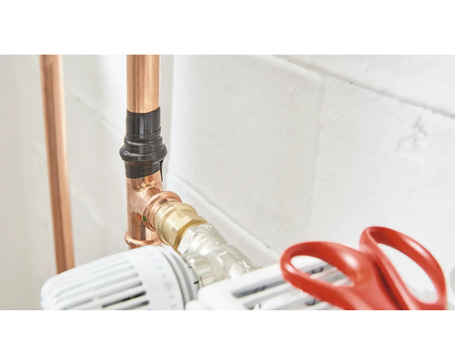 Měděný potrubní systém s izolací potrubí a termostatickým ventilem radiátoru.