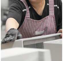 Osoba se zástěrou pracuje na keramickém umyvadle.