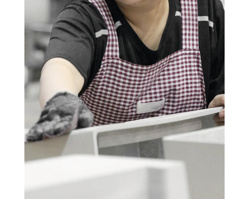 Osoba v zástěře pracuje na výrobku.