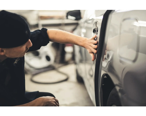 Muž kontroluje dveře auta na poškození.