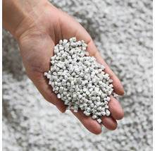 Ruka drží dávku steliva pro kočky.