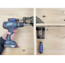 Osoba šroubuje akumulátorovým šroubovákem obrobek, který je upevněn pomocí rohového svěrky.