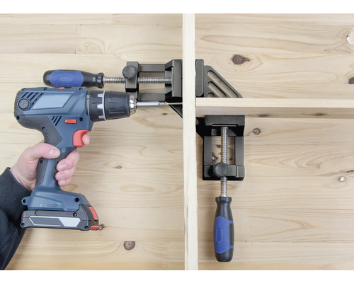 Osoba šroubuje akumulátorovým šroubovákem obrobek, který je upevněn pomocí rohového svěrky.