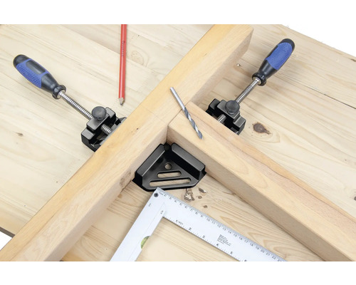 Pracovní stůl s dřevem, šroubovací svěrky, úhelník a vrták