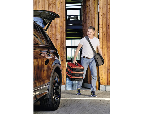 Muž nese tři kufříky s nářadím k autu