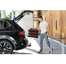 Muž vykládá červené kufříky s nářadím z černého auta