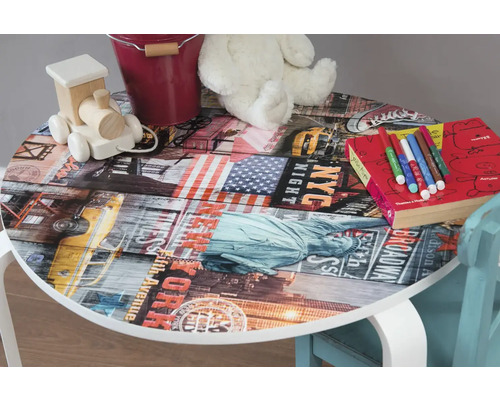 Dětský stůl s motivem New Yorku, leží na něm hračky, tužky a kniha