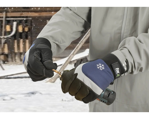 Osoba má na sobě pracovní rukavice a drží vrtačku.