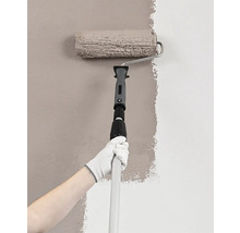 Malíř s válečkem a teleskopickou tyčí maluje stěnu