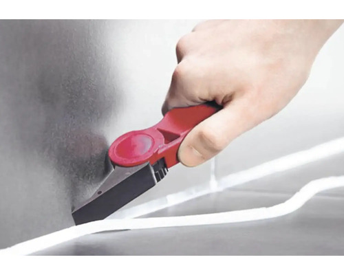 Ruka používá nástroj na odstraňování spár k odstranění spáry.