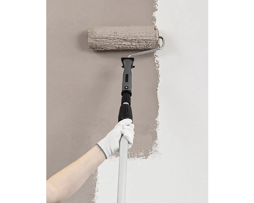 Osoba maluje stěnu válečkem a teleskopickou tyčí