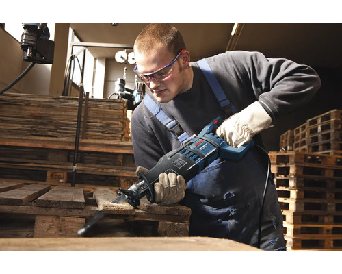 Muž řeže dřevěnou desku pilou ocaskou.