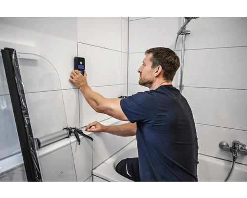 Muž používá skener stěn v koupelně k rekonstrukci koupelny.