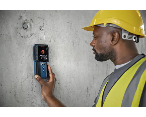 Stavební dělník používá detektor Bosch na betonové zdi