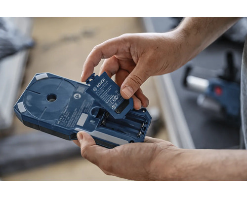 Muž vkládá baterii do vyhledávače Bosch