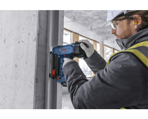 Pracovník používá nastřelovací pistoli na staveništi.