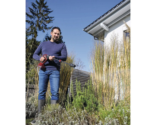 Muž používá akumulátorový tlakový čistič na zahradě.