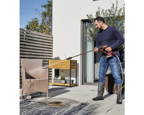 Muž čistí terasu venku pomocí tlakové myčky.