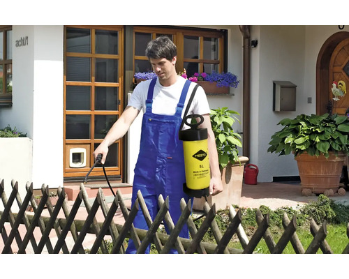 Muž používá zahradní postřikovač Mesto pro zahradničení před domem.